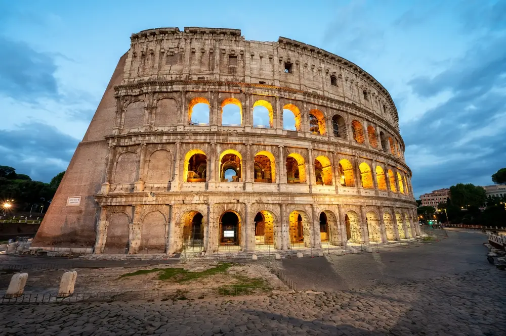 evening view of the colosseum with its arches illuminated by lights